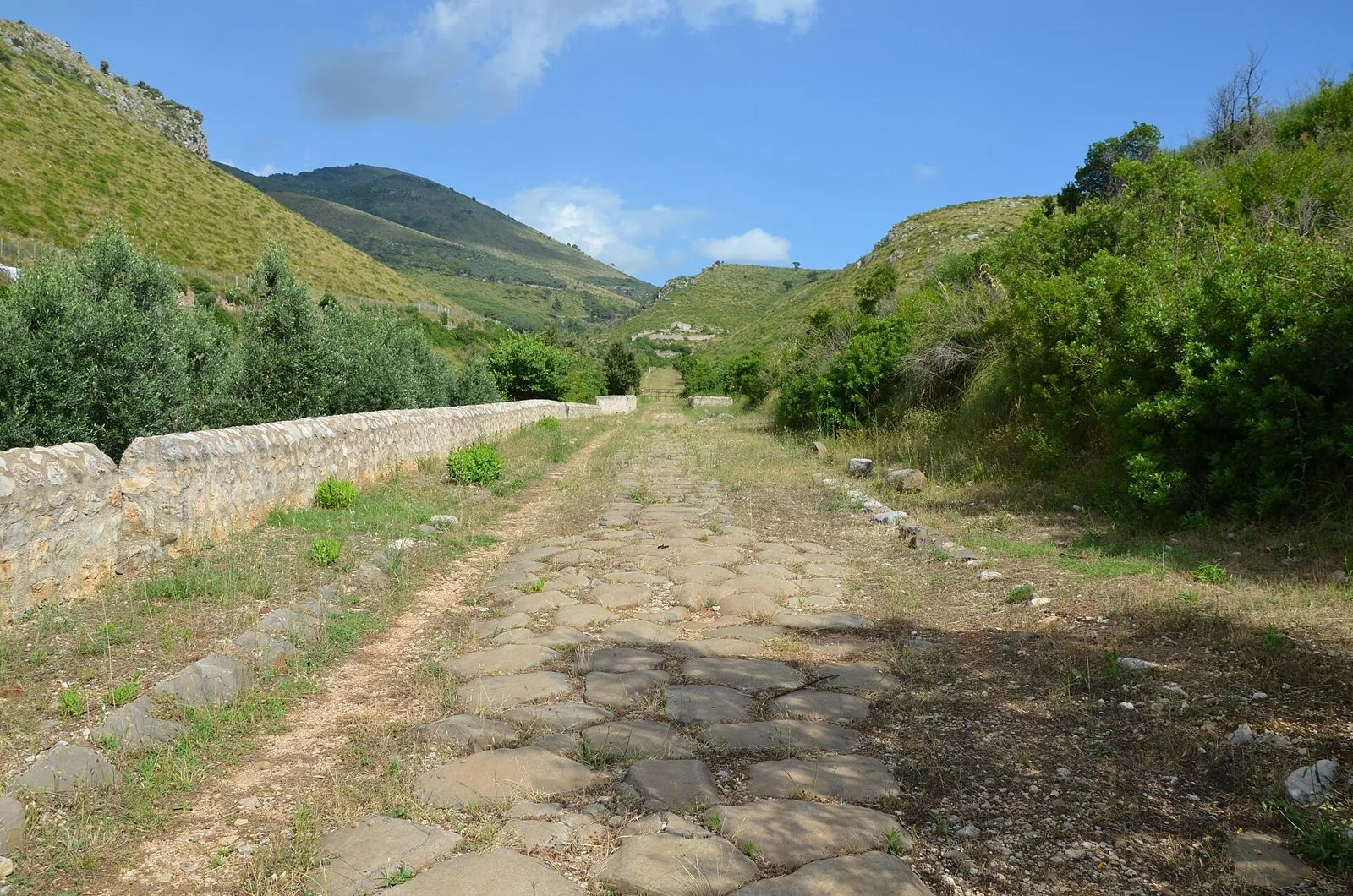 Il basolato romano della Via Appia antica nella valle di Sant'Andrea, tra colline verdi e macchia, nel Parco dei Monti Aurunci verso Itri